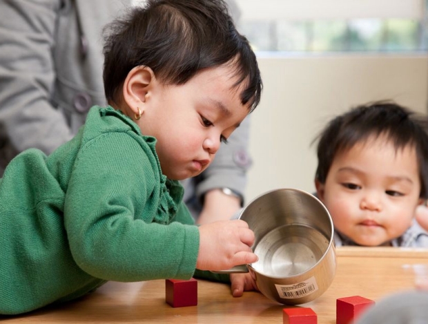 Small children playing with blocks and container